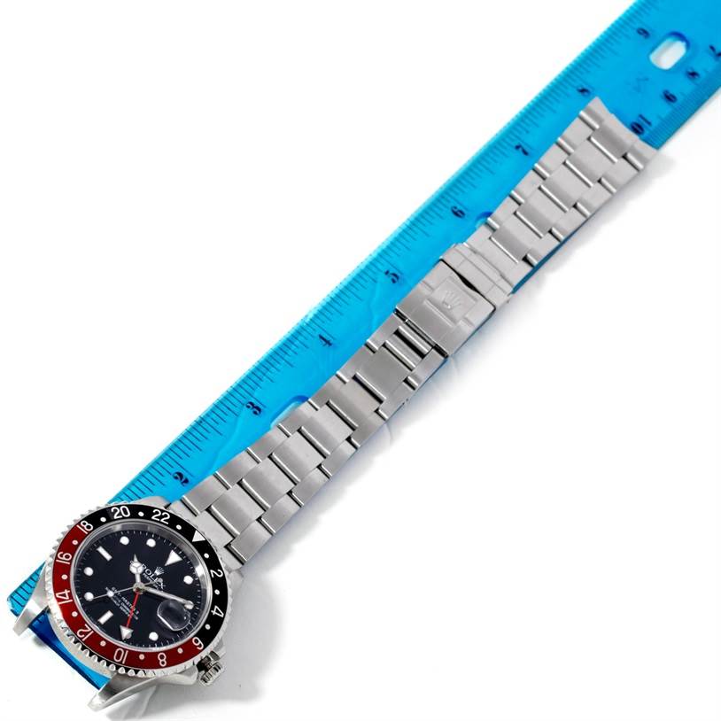 The Rolex GMT-Master 16710 Men
s Stainless Steel Black Dial 16710 Men
s Stainless Steel Black Dial watch is shown from a top-down angle, displaying the full length of the watch band and the face next to a ruler.