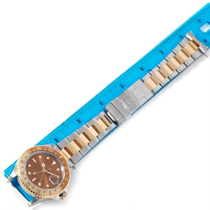 The image shows a Rolex GMT-Master 16713 Men's Stainless Steel Brown Dial 16713 Men's Stainless Steel Brown Dial watch laid flat beside a blue ruler, highlighting the face and bracelet.