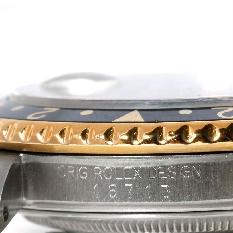 This close-up image of a Rolex GMT-Master 16713 Men's Stainless Steel Black Dial 16713 Men's Stainless Steel Black Dial shows the bezel, case side, and engraved model number 16713.