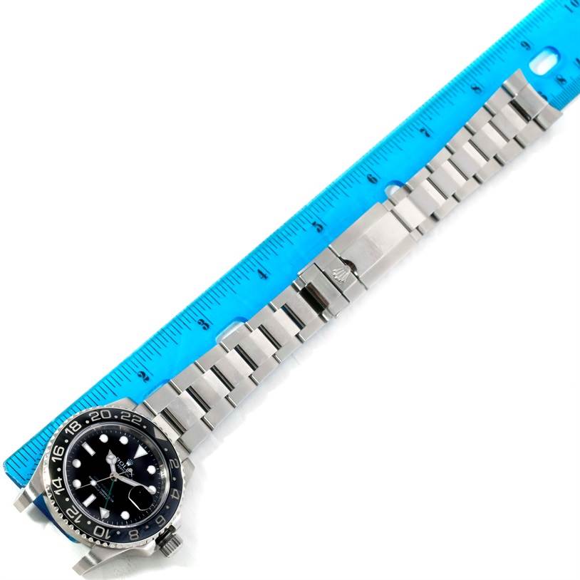 The image shows a Rolex GMT-Master 116710 Men's Stainless Steel Black Dial 116710 Men's Stainless Steel Black Dial watch laying flat, with the face and metal strap fully visible, alongside a blue ruler for scale.