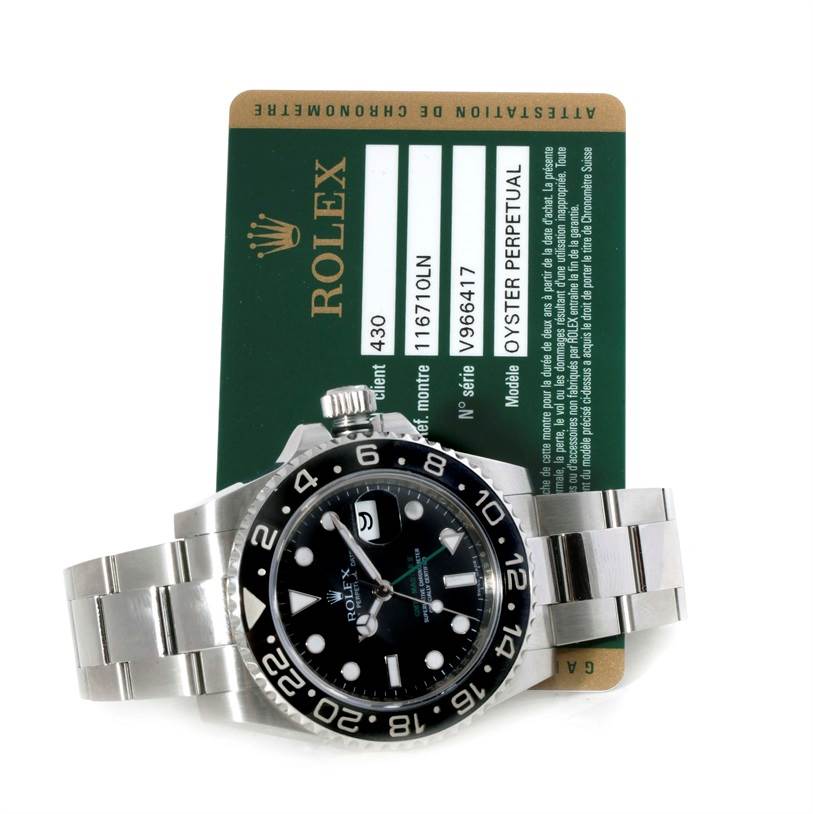 This image shows a Rolex GMT-Master 116710 Men's Stainless Steel Black Dial 116710 Men's Stainless Steel Black Dial watch laying atop its warranty card, displaying the bezel, dial, and part of the bracelet.