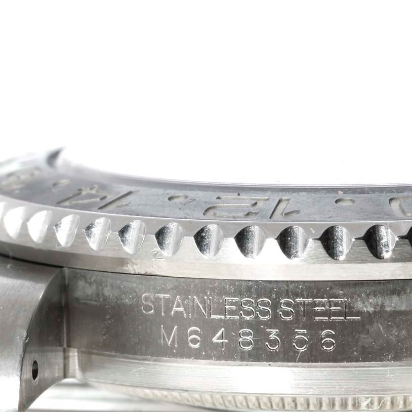 This image shows a close-up of the Rolex GMT-Master 116710 Men's Stainless Steel Black Dial 116710 Men's Stainless Steel Black Dial's bezel and the side of its stainless steel case with engraved serial number.