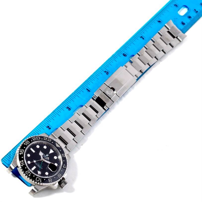 The Rolex GMT-Master 116710 Men's Stainless Steel Black Dial 116710 Men's Stainless Steel Black Dial watch is shown from a top-down angle, including the case, dial, bezel, and metal bracelet laid next to a blue ruler.