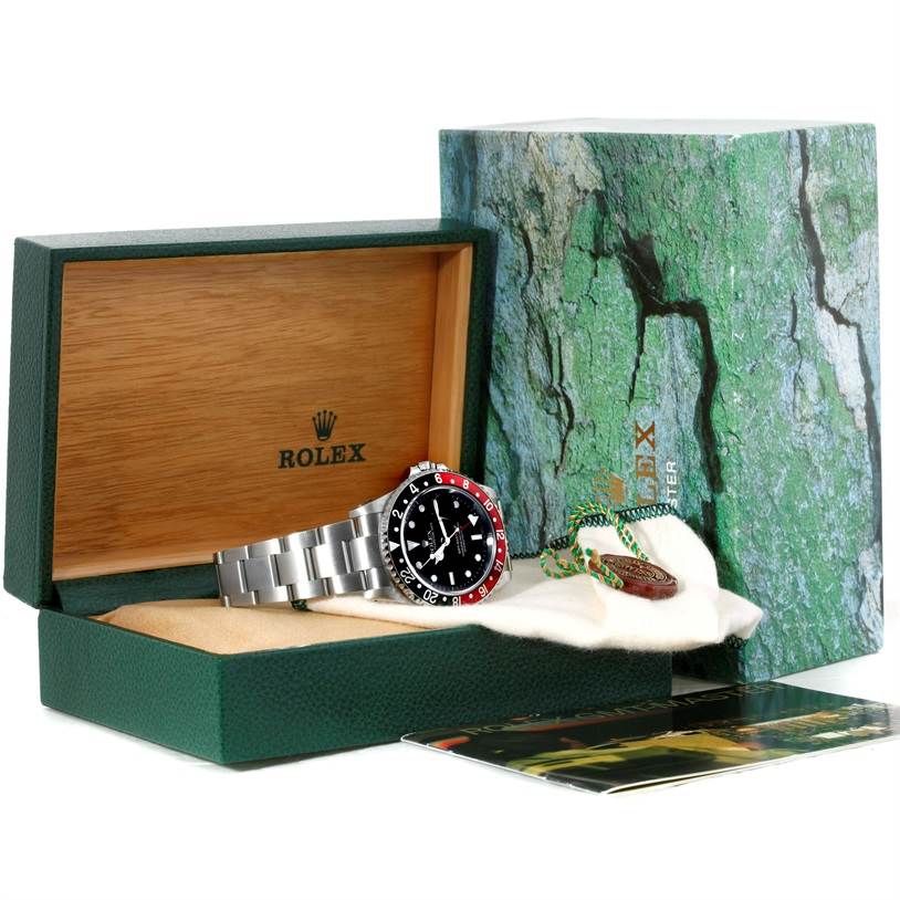 The image shows a Rolex GMT-Master 16710 Men's Stainless Steel Black Dial 16710 Men's Stainless Steel Black Dial watch and accessories from a side angle, with the watch inside a green presentation box.