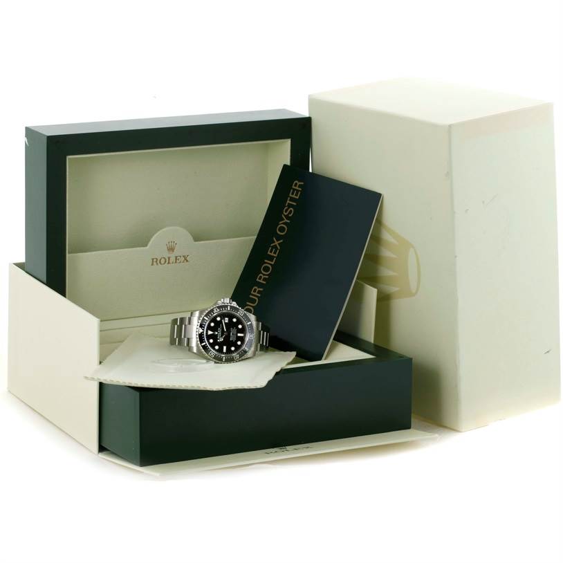 A Rolex Sea-Dweller 116600 Men
s Stainless Steel Black Dial 116600 Men
s Stainless Steel Black Dial watch is shown at an angle inside an open box, accompanied by booklets and a protective cloth.