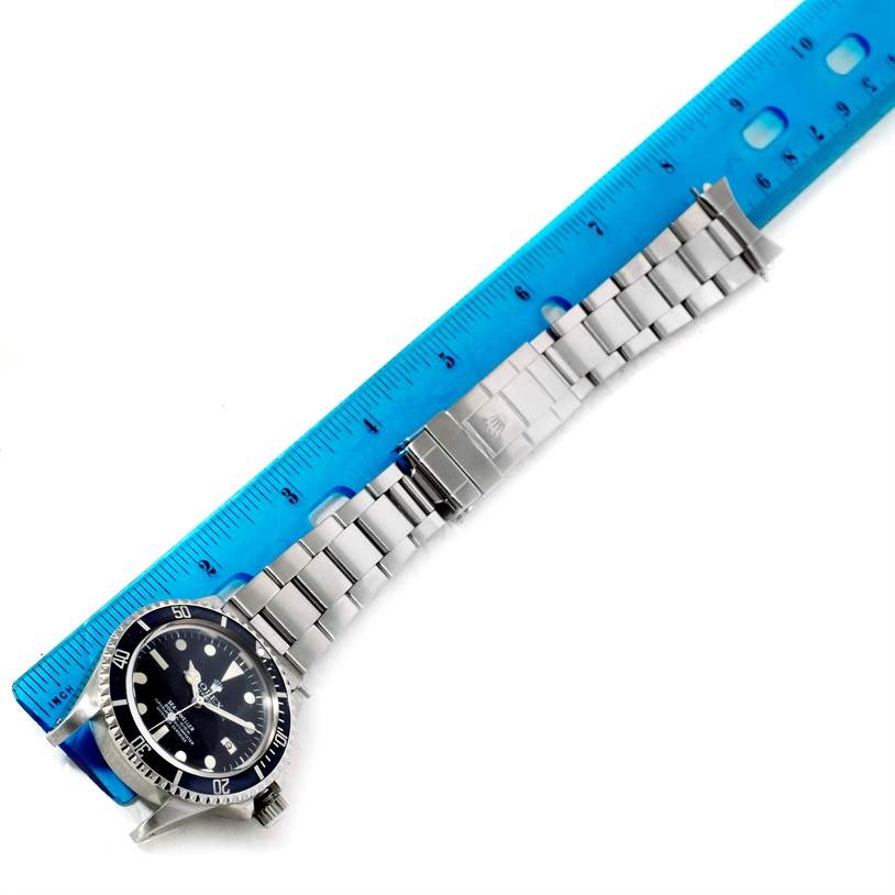 The image shows a top view of a Rolex Sea-Dweller 1665 Men's Stainless Steel Black Dial 1665 Men's Stainless Steel Black Dial watch, including the face, bezel, and stainless steel bracelet, positioned next to a blue ruler.