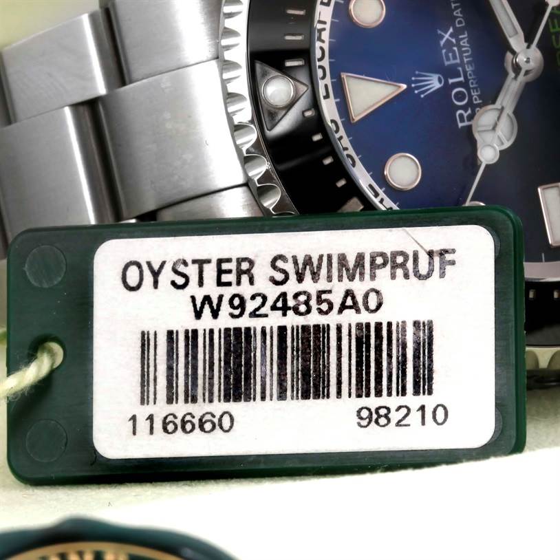 The image shows a close-up of the Rolex Sea-Dweller 116660 Men
s Stainless Steel Blue Dial 116660 Men
s Stainless Steel Blue Dial watch face, bezel, part of the bracelet, and a green tag with product details.