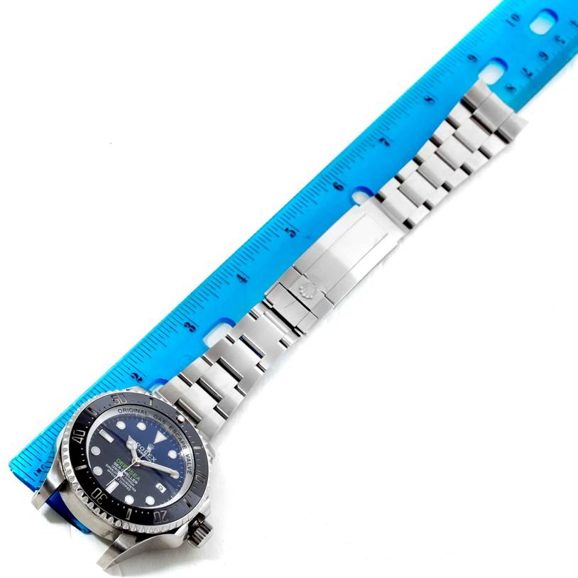 The image shows a Rolex Sea-Dweller 116660 Men
s Stainless Steel Blue Dial 116660 Men
s Stainless Steel Blue Dial watch laid flat with a metal bracelet alongside a ruler for size reference.