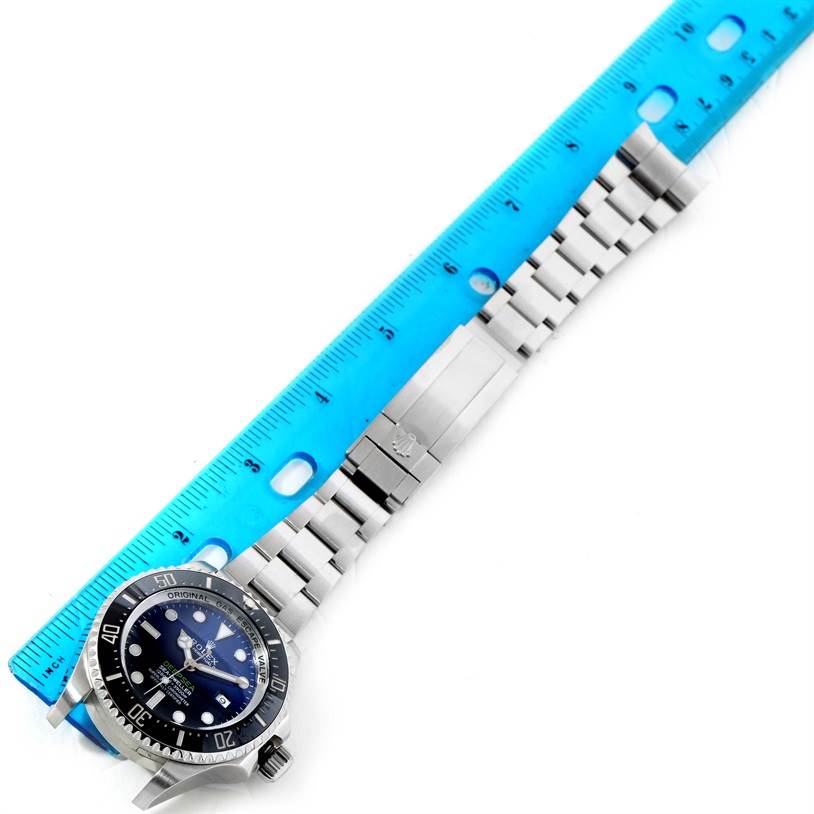 The Rolex Sea-Dweller 116660 Men's Stainless Steel Blue Dial 116660 Men's Stainless Steel Blue Dial watch is shown partially from the top, alongside a ruler, displaying its face and stainless steel strap.