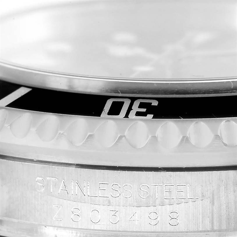 This close-up image of a Rolex Sea-Dweller 16600 Men's Stainless Steel Black Dial 16600 Men's Stainless Steel Black Dial watch shows part of the bezel and the side of the case with engraved serial information.