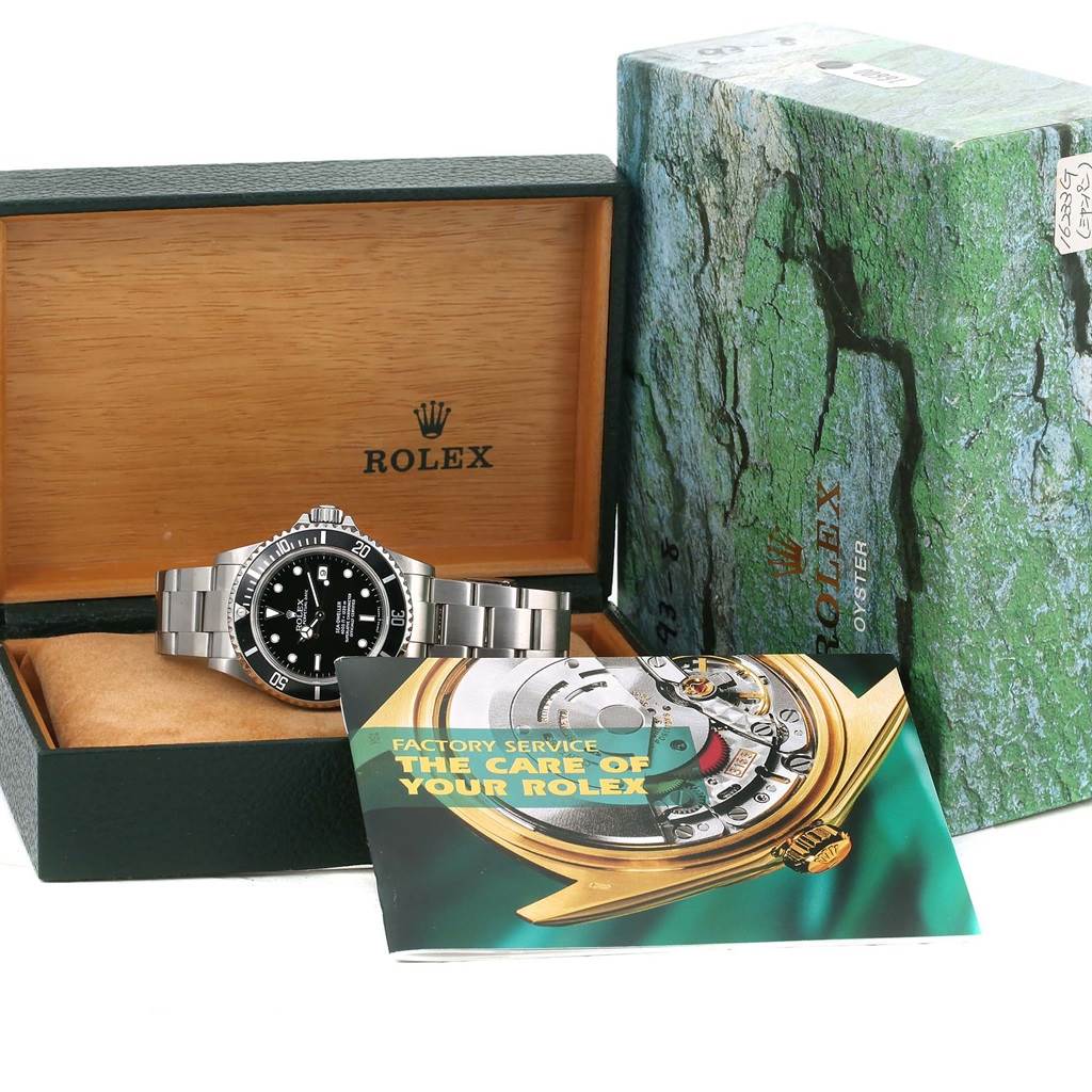 The image shows a Rolex Sea-Dweller 16600 Men
s Stainless Steel Black Dial 16600 Men
s Stainless Steel Black Dial watch at a front angle inside an open box, alongside a care booklet and the outer packaging.