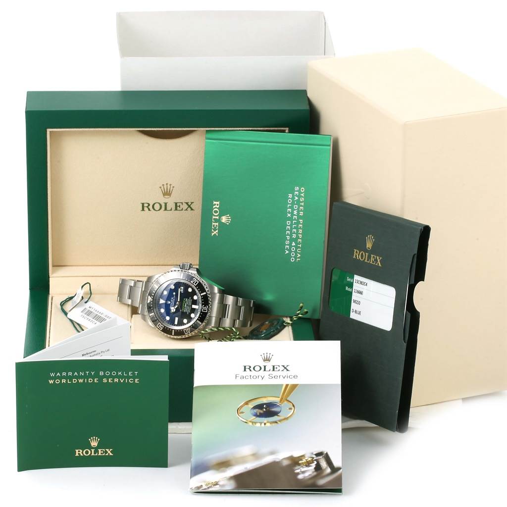 The image shows a Rolex Sea-Dweller 116660 Men
s Stainless Steel Blue Dial 116660 Men
s Stainless Steel Blue Dial watch with its box, booklets, and accessories from a front angle.