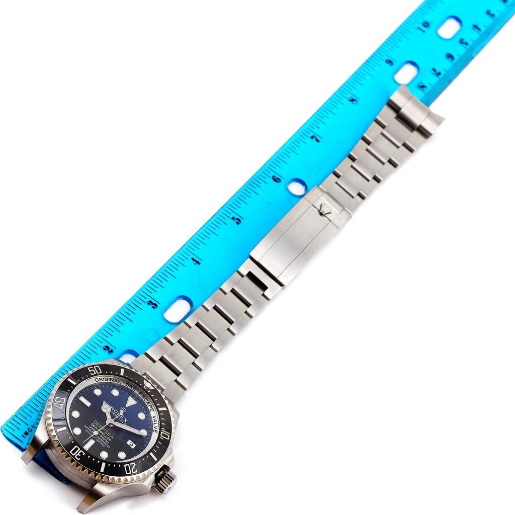 The image shows a Rolex Sea-Dweller 116660 Men's Stainless Steel Blue Dial 116660 Men's Stainless Steel Blue Dial watch laid flat with a blue ruler alongside, highlighting its entire bracelet and dial.