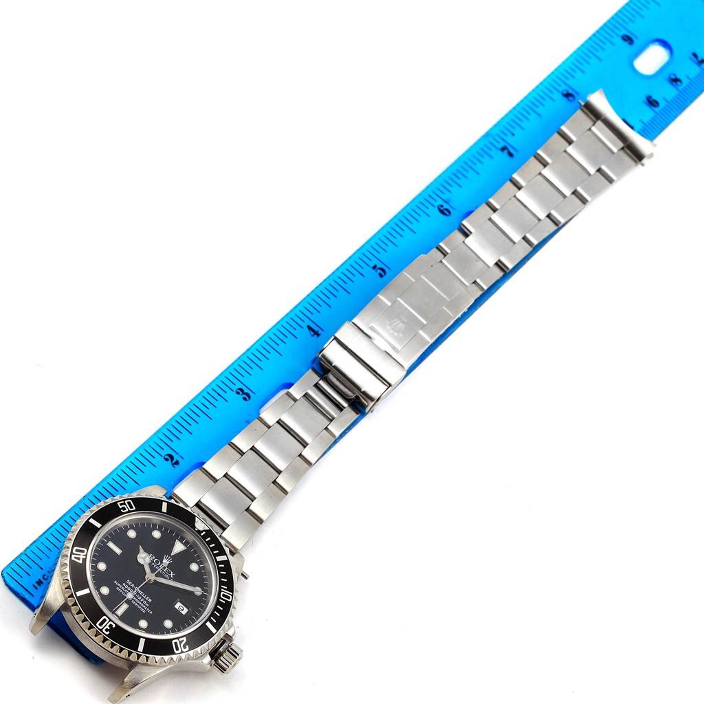 The Rolex Sea-Dweller 16600 Men's Stainless Steel Black Dial 16600 Men's Stainless Steel Black Dial watch is shown flat and extended, with a full view of the watch face and bracelet alongside a blue ruler.