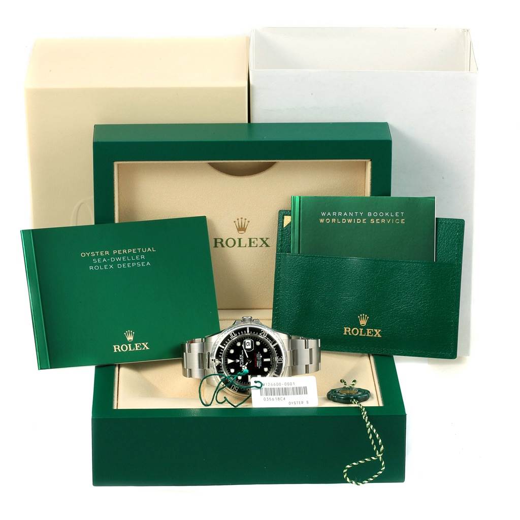 The image shows a Rolex Sea-Dweller 126600 Men
s Stainless Steel Black Dial 126600 Men
s Stainless Steel Black Dial watch with its box, warranty booklet, and other accessories, viewed from the front.