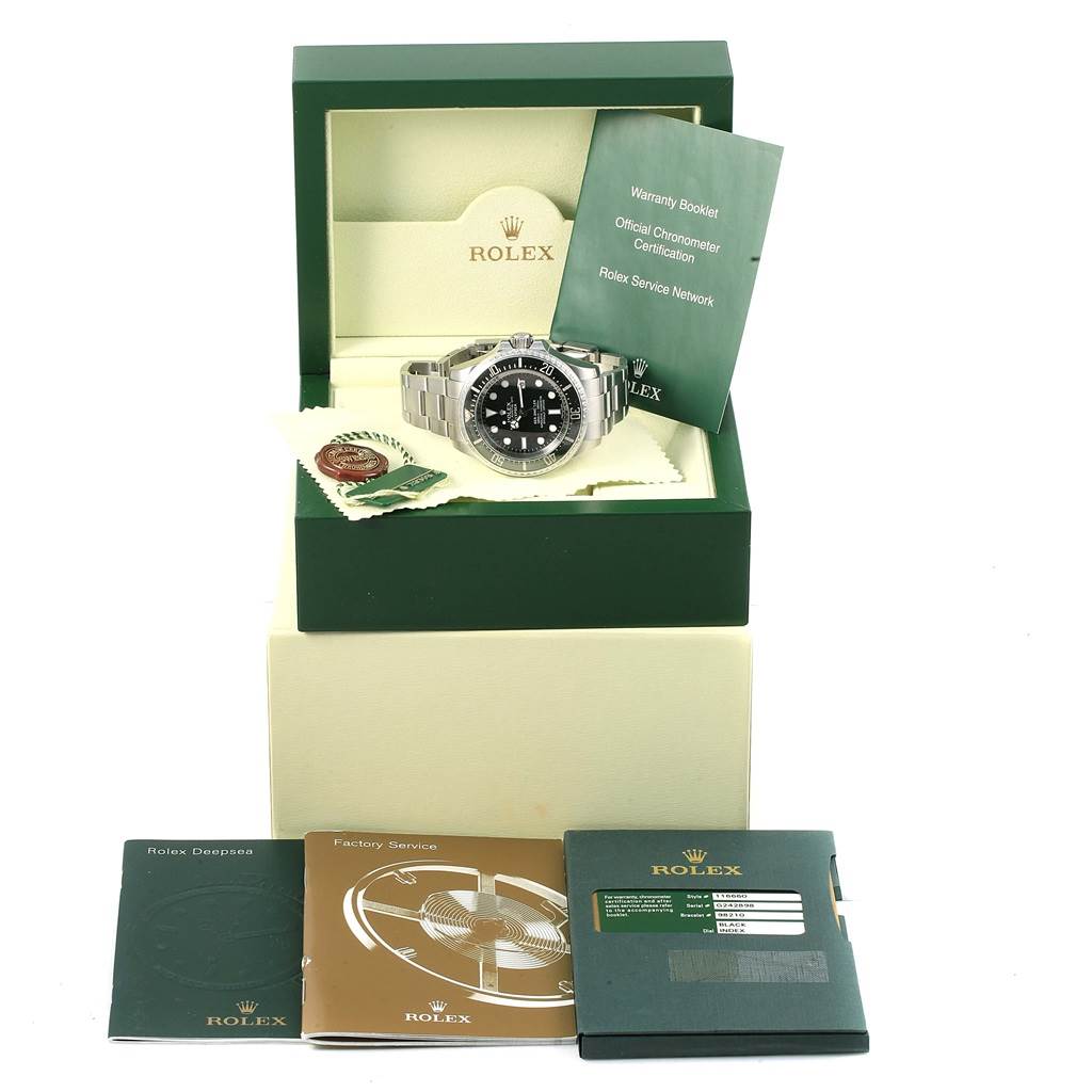 The image shows a Rolex Sea-Dweller 116660 Men
s Stainless Steel Black Dial 116660 Men
s Stainless Steel Black Dial watch in its box with warranty booklets and additional documentation placed around it.