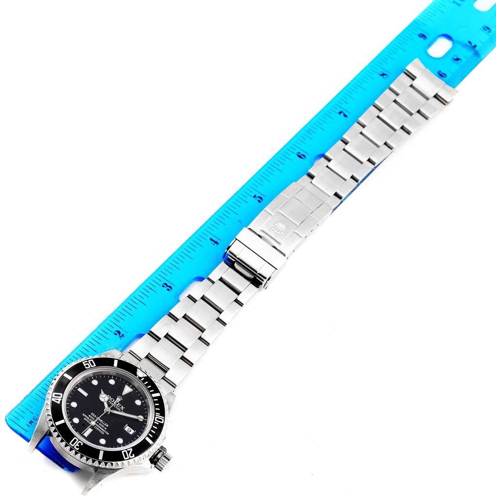 The image shows a full view of the Rolex Sea-Dweller 16600 Men
s Stainless Steel Black Dial 16600 Men
s Stainless Steel Black Dial watch model laid flat next to a blue ruler, displaying the bracelet and dial.