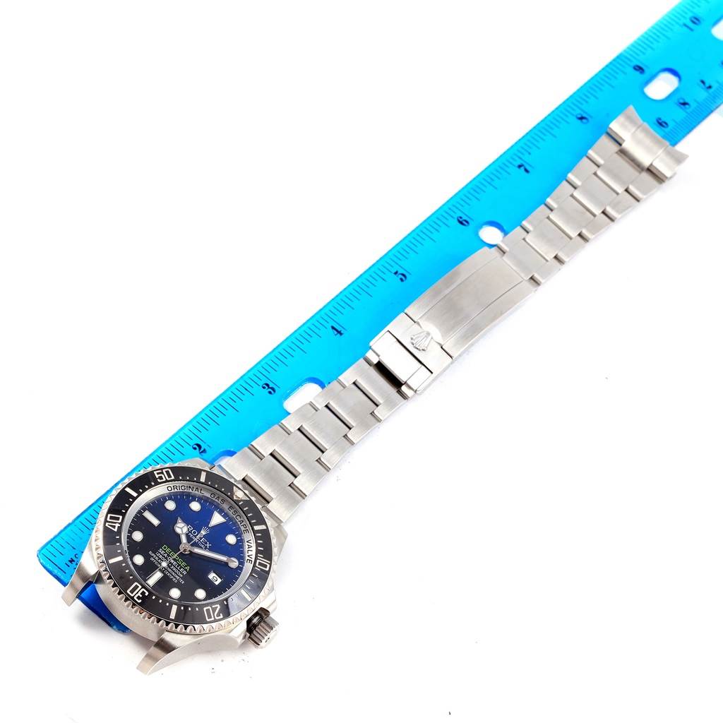 This image shows a top-down view of a Rolex Sea-Dweller 116660 Men's Stainless Steel Blue Dial 116660 Men's Stainless Steel Blue Dial watch laid alongside a blue ruler.