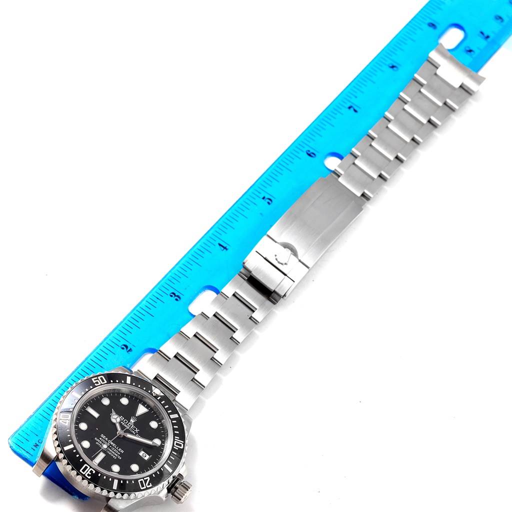The image shows a Rolex Sea-Dweller 116600 Men's Stainless Steel Black Dial 116600 Men's Stainless Steel Black Dial watch laid flat with its bracelet next to a blue ruler.