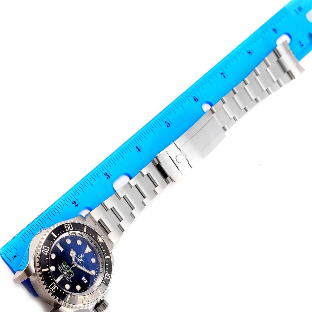 The Rolex Sea-Dweller 116660 Men's Stainless Steel Blue Dial 116660 Men's Stainless Steel Blue Dial watch is shown from an overhead angle, featuring its bezel, dial, and metal bracelet next to a measuring ruler.