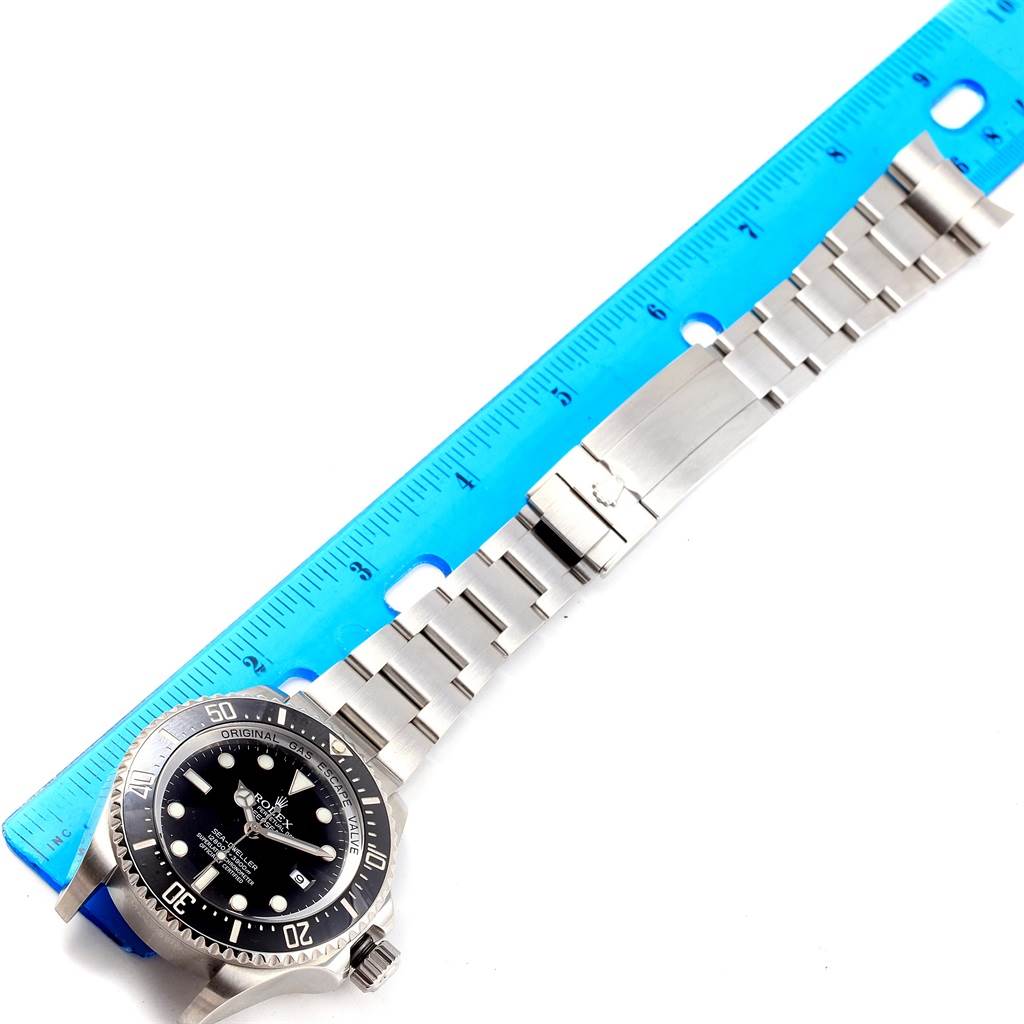 The Rolex Sea-Dweller 116660 Men's Stainless Steel Black Dial 116660 Men's Stainless Steel Black Dial is shown from a top-down angle with its full stainless steel band and clasp visible next to a ruler.