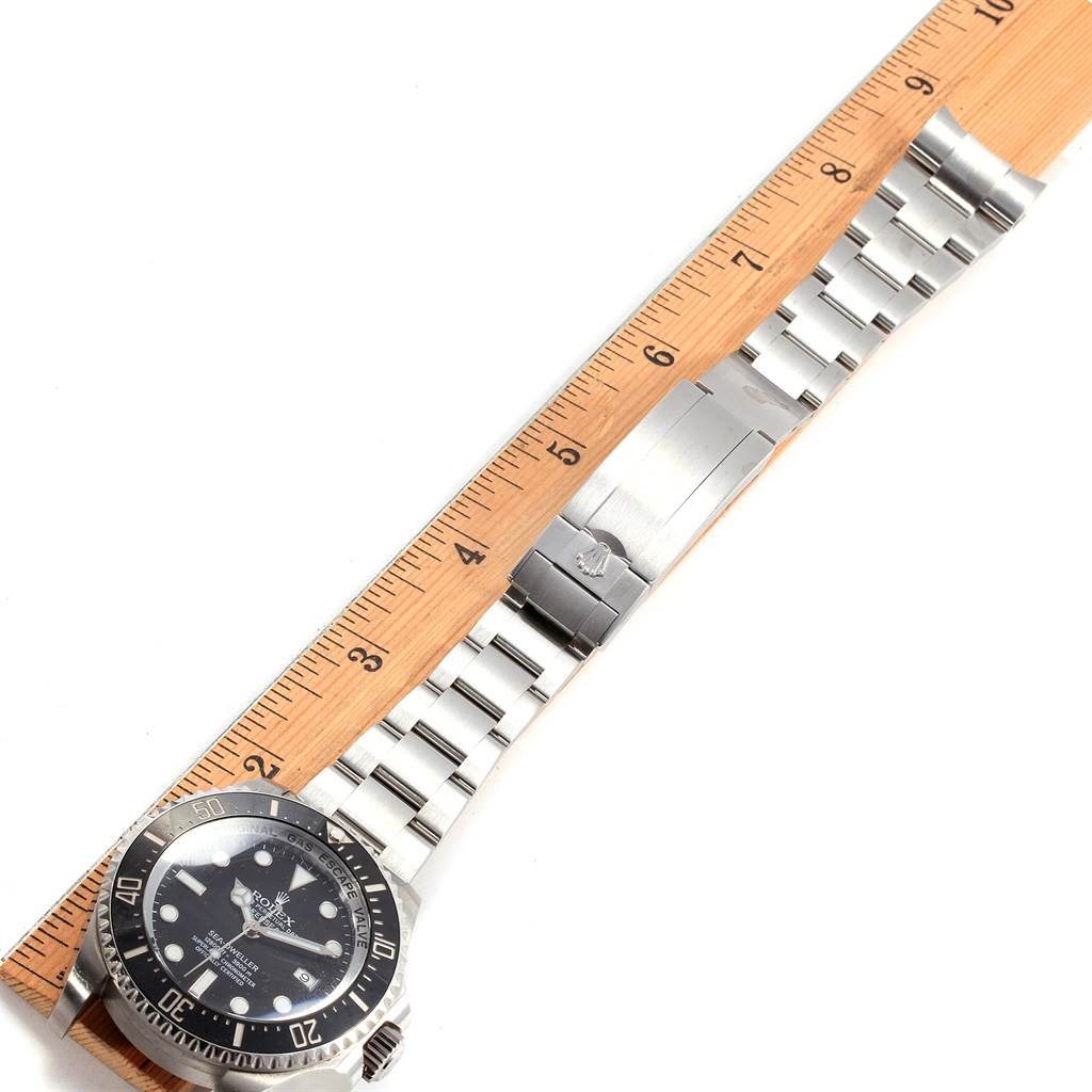 The image shows a top view of a Rolex Sea-Dweller 116660 Men
s Stainless Steel Black Dial 116660 Men
s Stainless Steel Black Dial watch, displaying its face, bezel, and entire metal bracelet alongside a measuring ruler.
