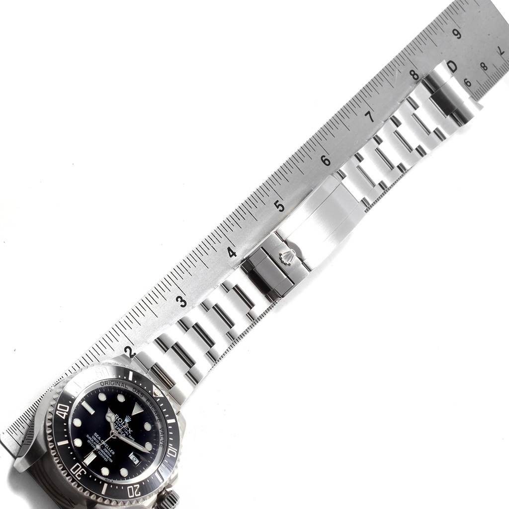 The image shows a top-down view of a Rolex Sea-Dweller 116660 Men
s Stainless Steel Black Dial 116660 Men
s Stainless Steel Black Dial watch and its metal bracelet next to a ruler.