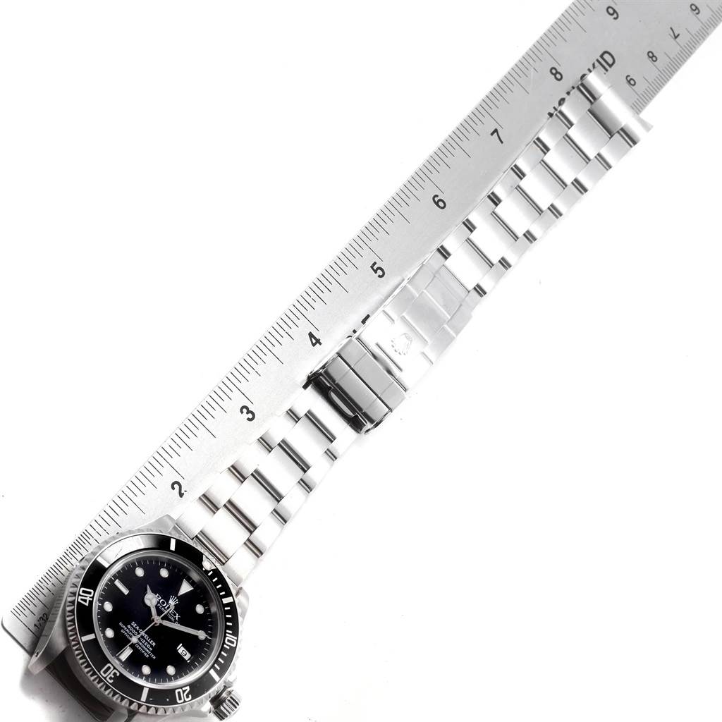 The image shows a flat lay view of a Rolex Sea-Dweller 16600 Men
s Stainless Steel Black Dial 16600 Men
s Stainless Steel Black Dial watch alongside a metal ruler, highlighting the watch
s bracelet and clasp.
