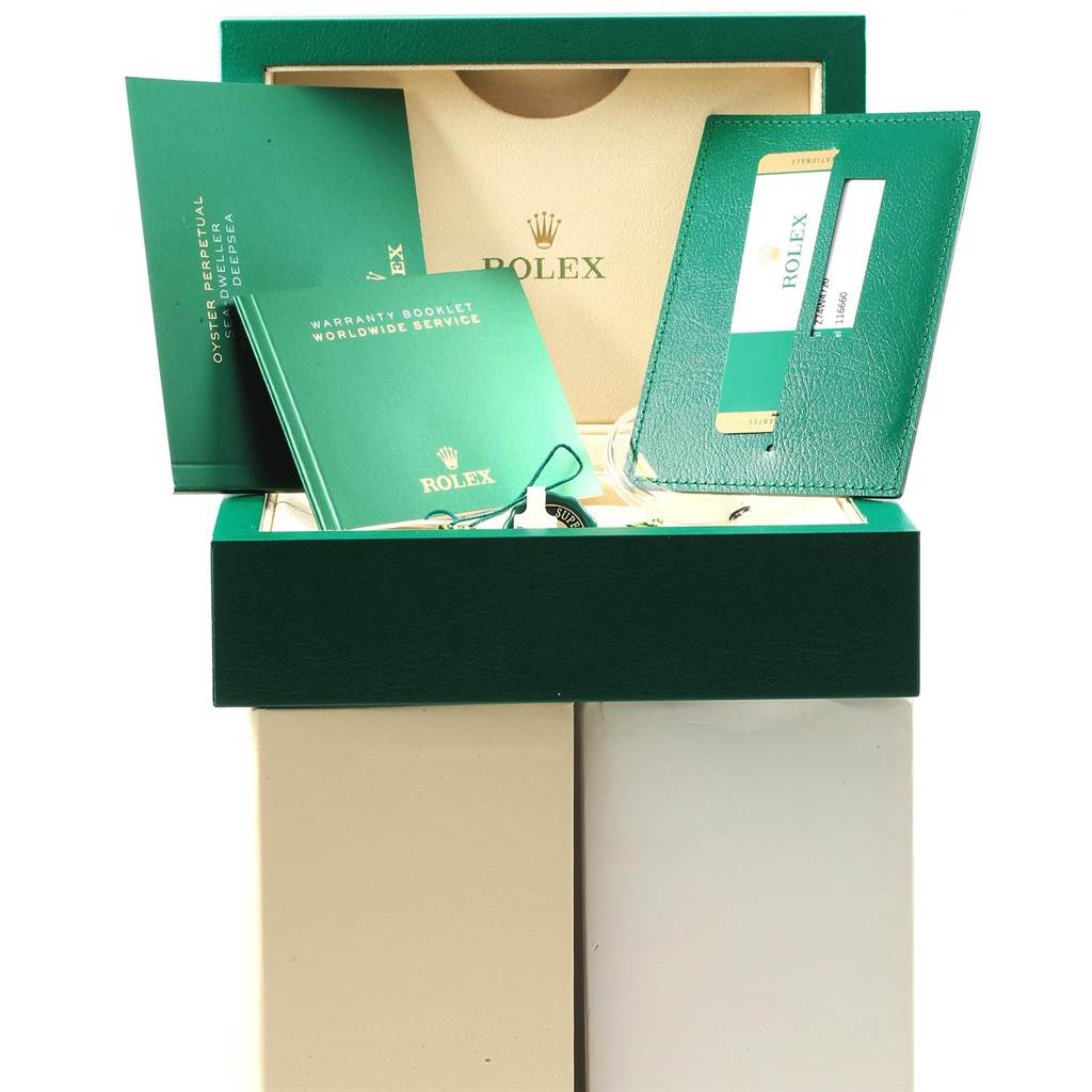 The image shows a Rolex Sea-Dweller 116660 Men
s Stainless Steel Blue Dial 116660 Men
s Stainless Steel Blue Dial watch box with accompanying booklets, a warranty card, and tags, revealed from a top-front angle.