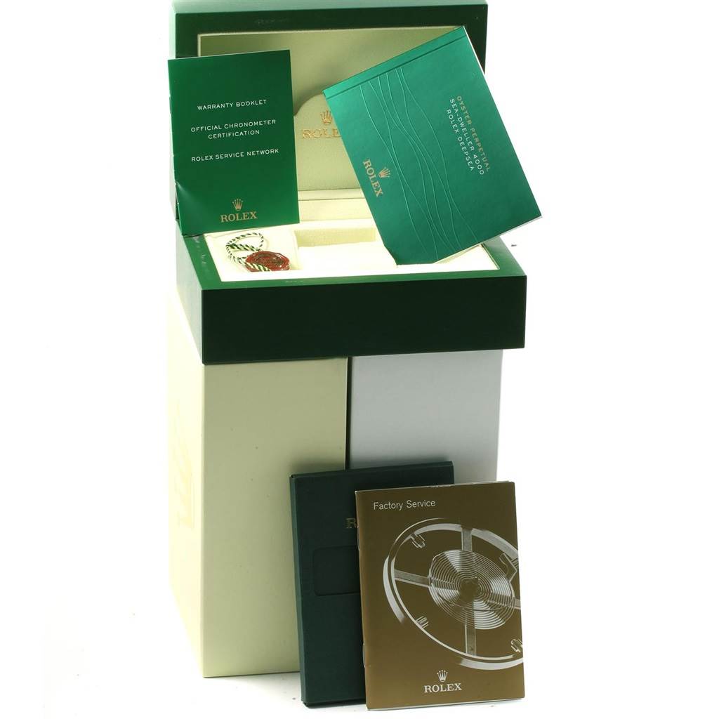 The image shows the packaging and booklets for a Rolex Sea-Dweller 116600 Men
s Stainless Steel Black Dial 116600 Men
s Stainless Steel Black Dial watch, including warranty and service manuals, photographed at an angle slightly above eye level.