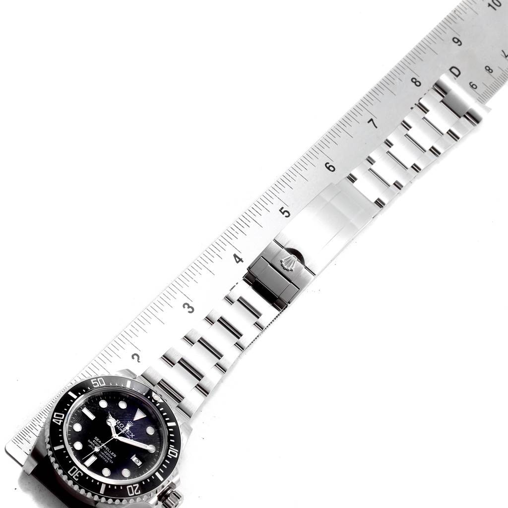 The image shows a top-down view of a Rolex Sea-Dweller 116600 Men
s Stainless Steel Black Dial 116600 Men
s Stainless Steel Black Dial watch with a stainless steel bracelet and clasp, measured against a ruler.