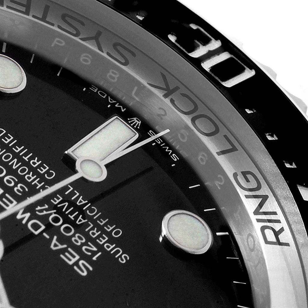 The image shows a close-up angle of the Rolex Sea-Dweller 126660 Men
s Stainless Steel Black Dial 126660 Men
s Stainless Steel Black Dial model featuring the dial, bezel, minute and hour markers, and part of the Ring Lock system.