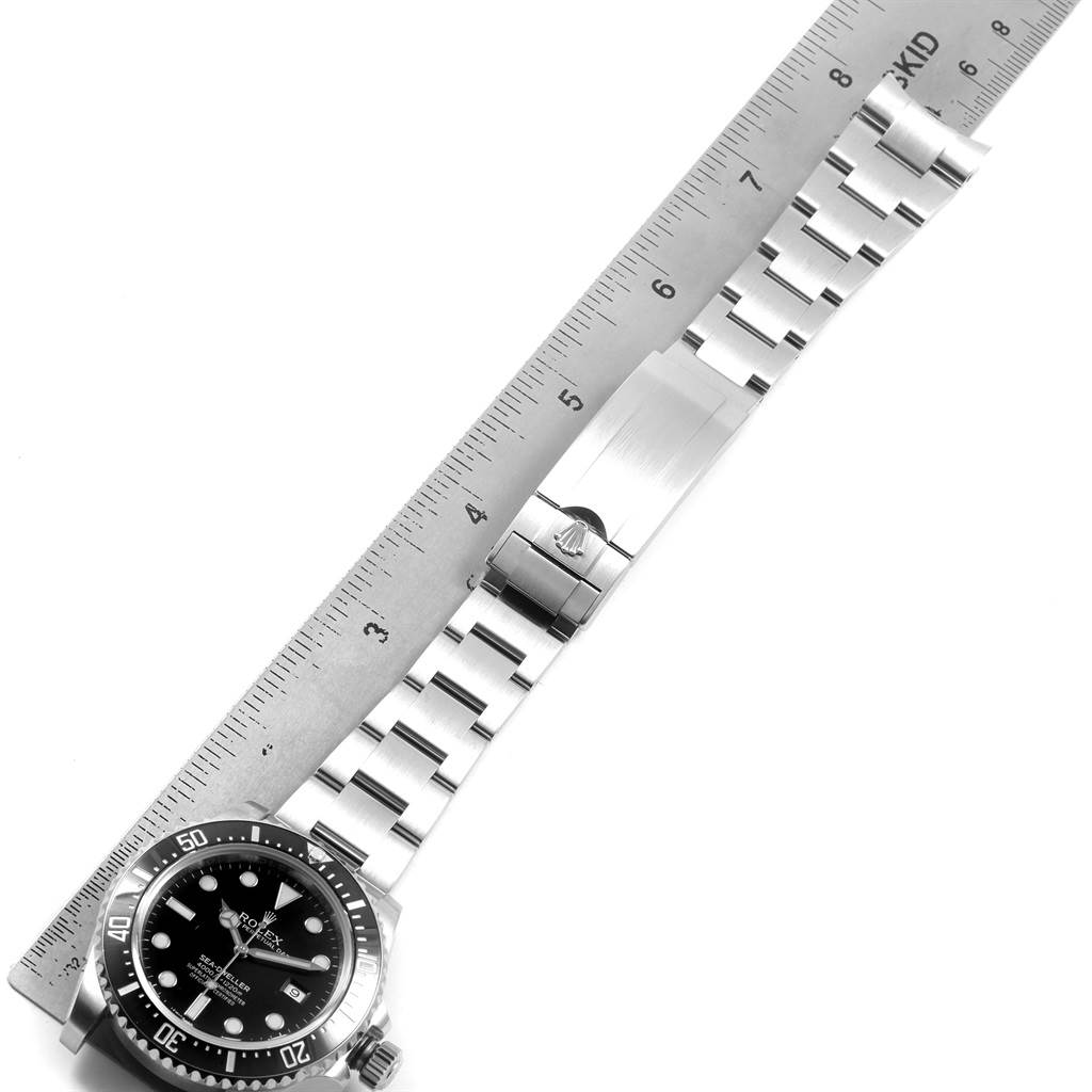The image shows the Rolex Sea-Dweller 116600 Men
s Stainless Steel Black Dial 116600 Men
s Stainless Steel Black Dial watch lying flat with its bracelet and clasp extended, aligned next to a ruler.