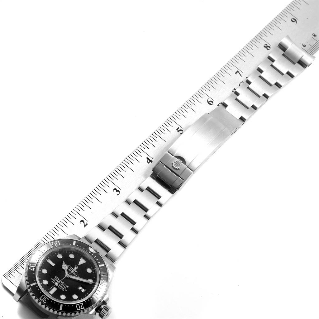 The image shows the Rolex Sea-Dweller 116600 Men
s Stainless Steel Black Dial 116600 Men
s Stainless Steel Black Dial watch face, bezel, and bracelet lying next to a ruler for size reference.