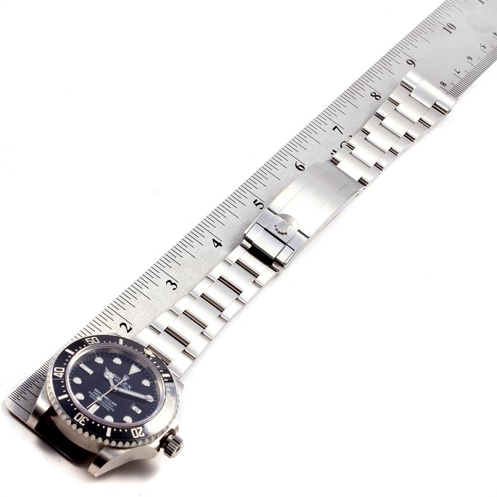 The image shows a flat, top-down view of a Rolex Sea-Dweller 116600 Men
s Stainless Steel Black Dial 116600 Men
s Stainless Steel Black Dial watch with a stainless steel bracelet, alongside a ruler for scale.