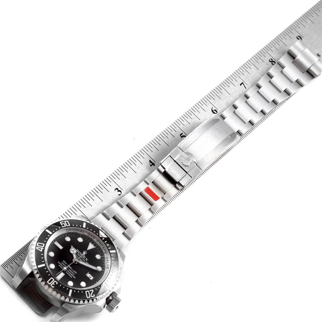 The image shows a Rolex Sea-Dweller 116660 Men
s Stainless Steel Black Dial 116660 Men
s Stainless Steel Black Dial watch face and bracelet at an angle, aligned with a ruler for measurement.
