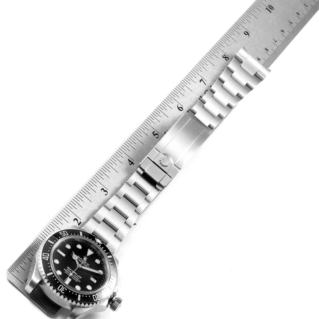 The image shows a Rolex Sea-Dweller 116600 Men
s Stainless Steel Black Dial 116600 Men
s Stainless Steel Black Dial watch laid flat against a ruler, displaying the watch case, dial, bracelet, and clasp.