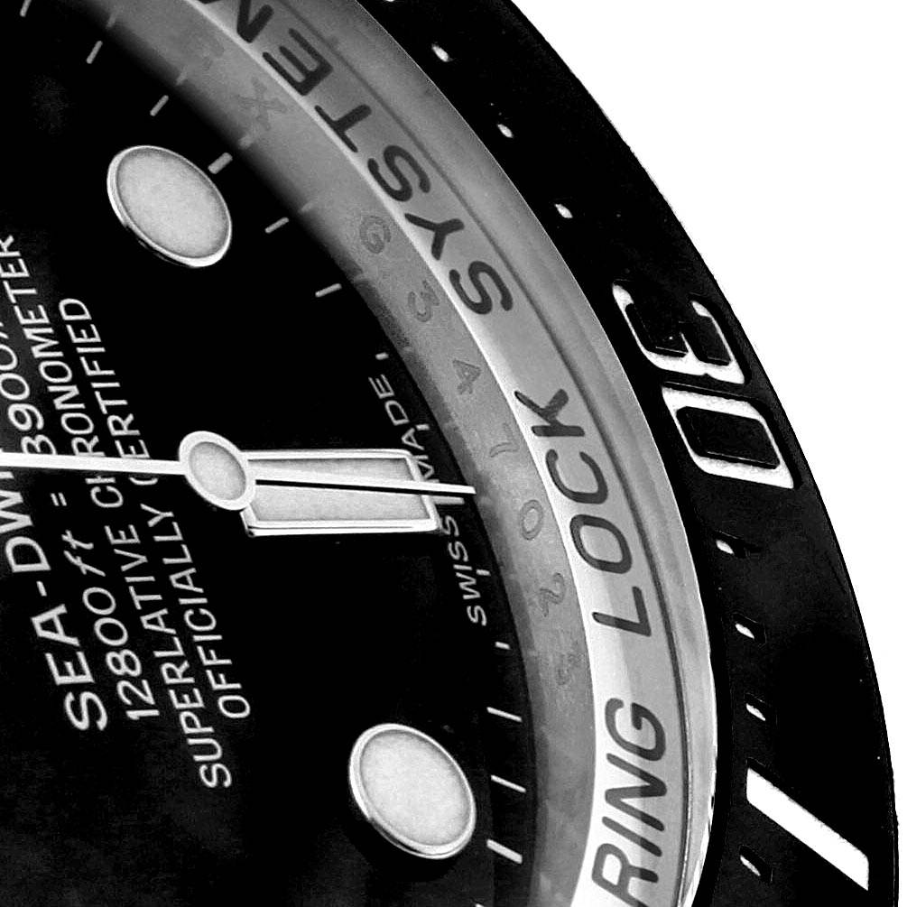 This image shows a close-up of the dial and bezel of a Rolex Sea-Dweller 116660 Men
s Stainless Steel Black Dial 116660 Men
s Stainless Steel Black Dial watch, highlighting the text and part of the minute hand.