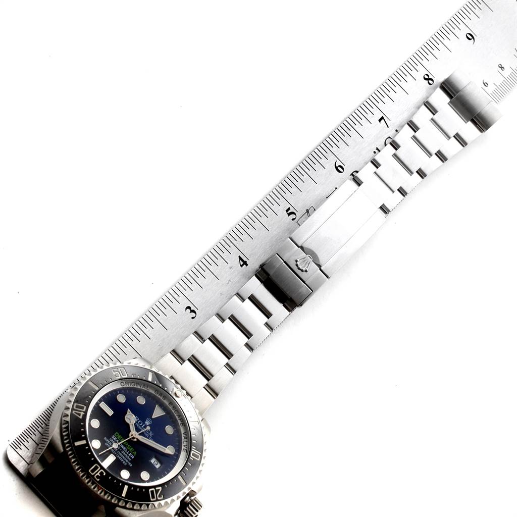 The image shows the Rolex Sea-Dweller 116660 Men
s Stainless Steel Blue Dial 116660 Men
s Stainless Steel Blue Dial watch face and part of the metal bracelet, aligned with a ruler.