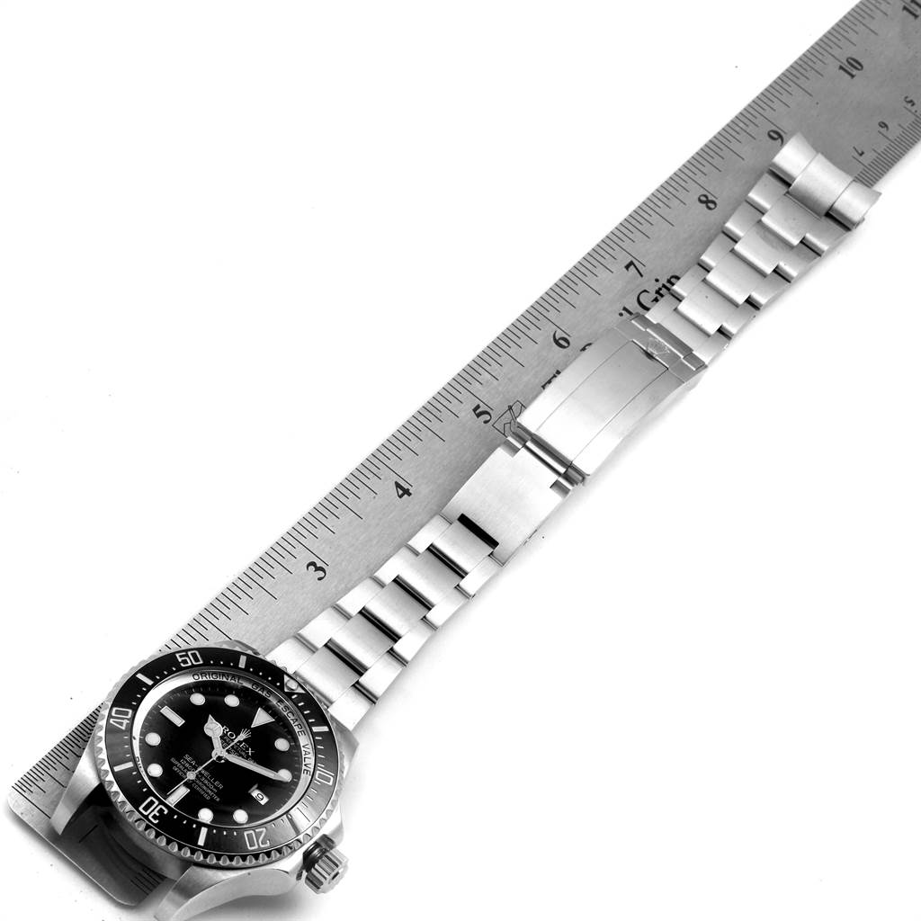 The image shows a top-down view of a Rolex Sea-Dweller 116660 Men
s Stainless Steel Black Dial 116660 Men
s Stainless Steel Black Dial watch with a metal ruler measuring its stainless steel bracelet.