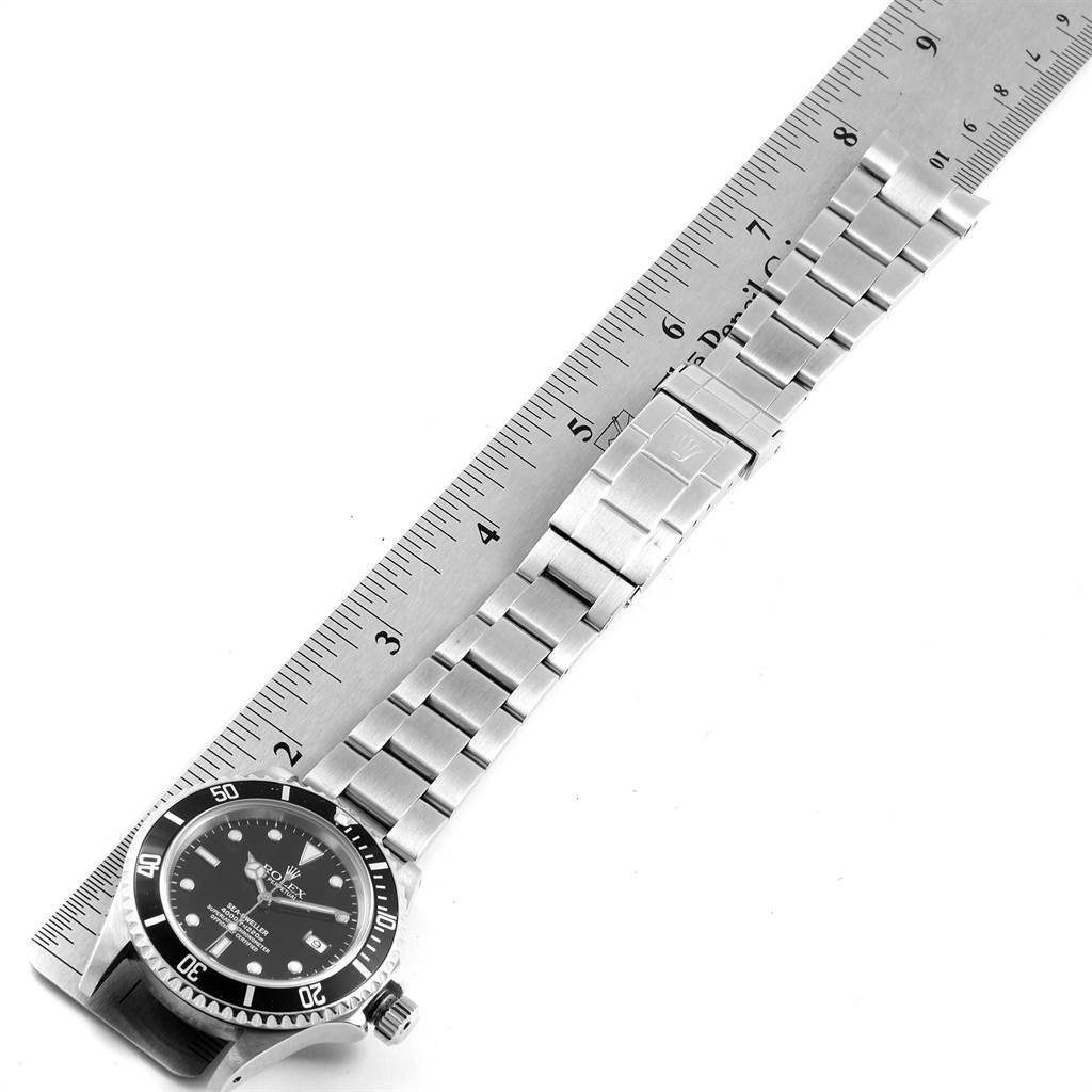 The image shows the Rolex Sea-Dweller 16600 Men
s Stainless Steel Black Dial 16600 Men
s Stainless Steel Black Dial watch and its metal bracelet alongside a ruler for scale.