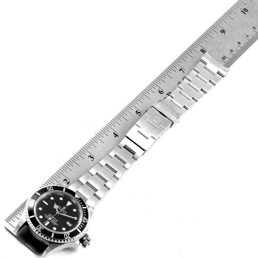 The image shows a Rolex Sea-Dweller 16600 Men
s Stainless Steel Black Dial 16600 Men
s Stainless Steel Black Dial watch and its bracelet laid flat alongside a ruler, displaying the watch face and clasp.