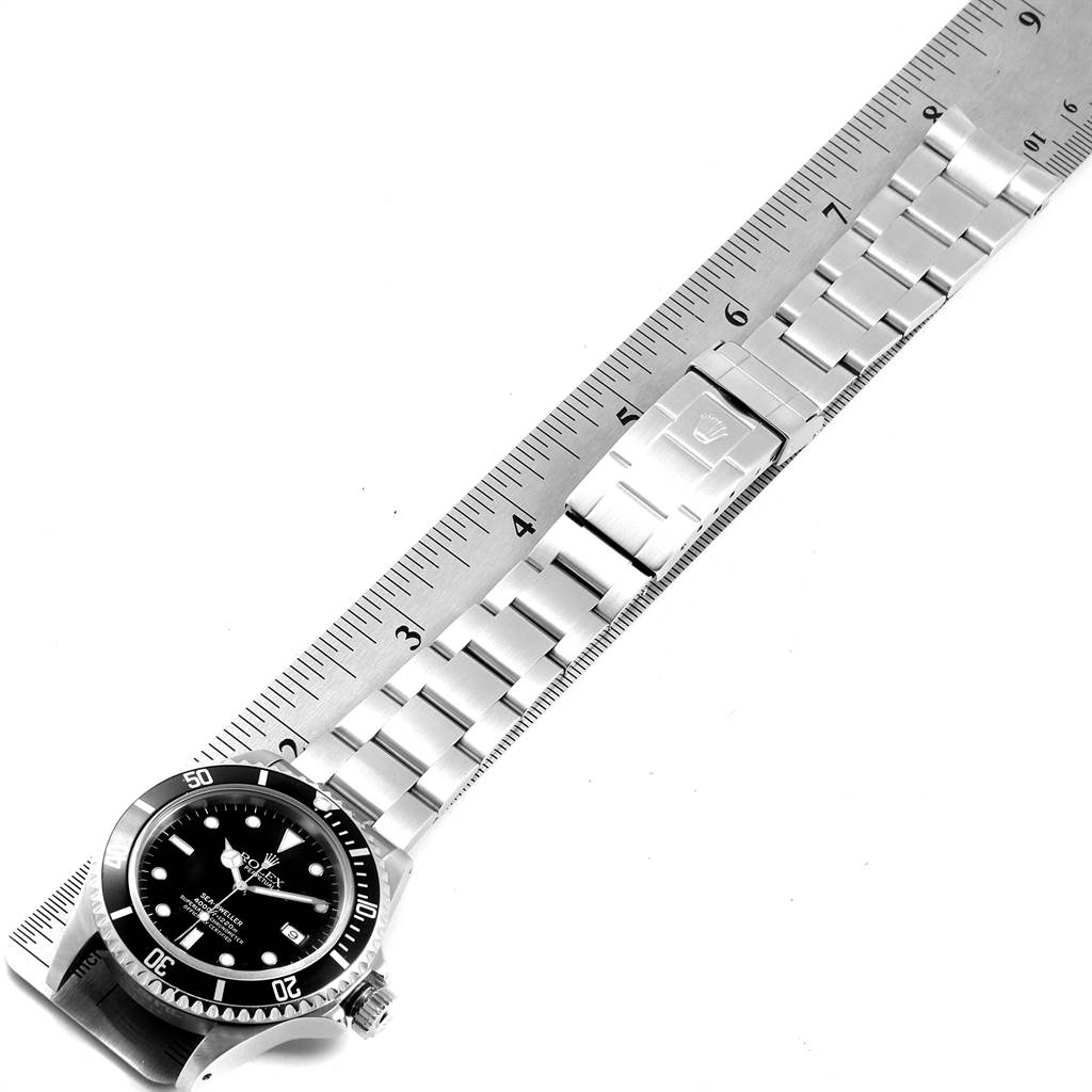 The image shows a top-down view of a Rolex Sea-Dweller 16600 Men
s Stainless Steel Black Dial 16600 Men
s Stainless Steel Black Dial watch with its watchband laid out against a ruler, displaying the bezel, dial, and bracelet.