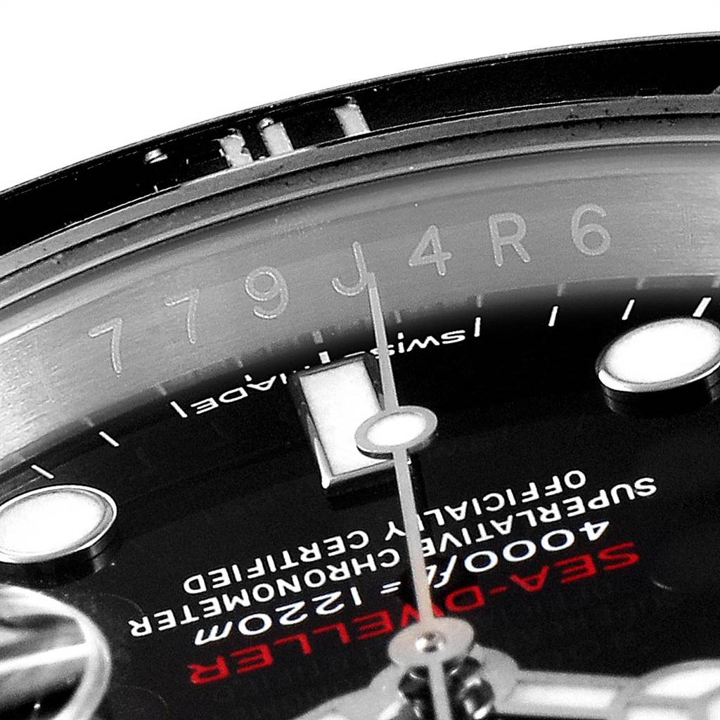 Close-up of the Rolex Sea-Dweller 126600 Men
s Stainless Steel Black Dial 126600 Men
s Stainless Steel Black Dial watch face, focusing on the serial number, text details, and a segment of the hour and minute markers.