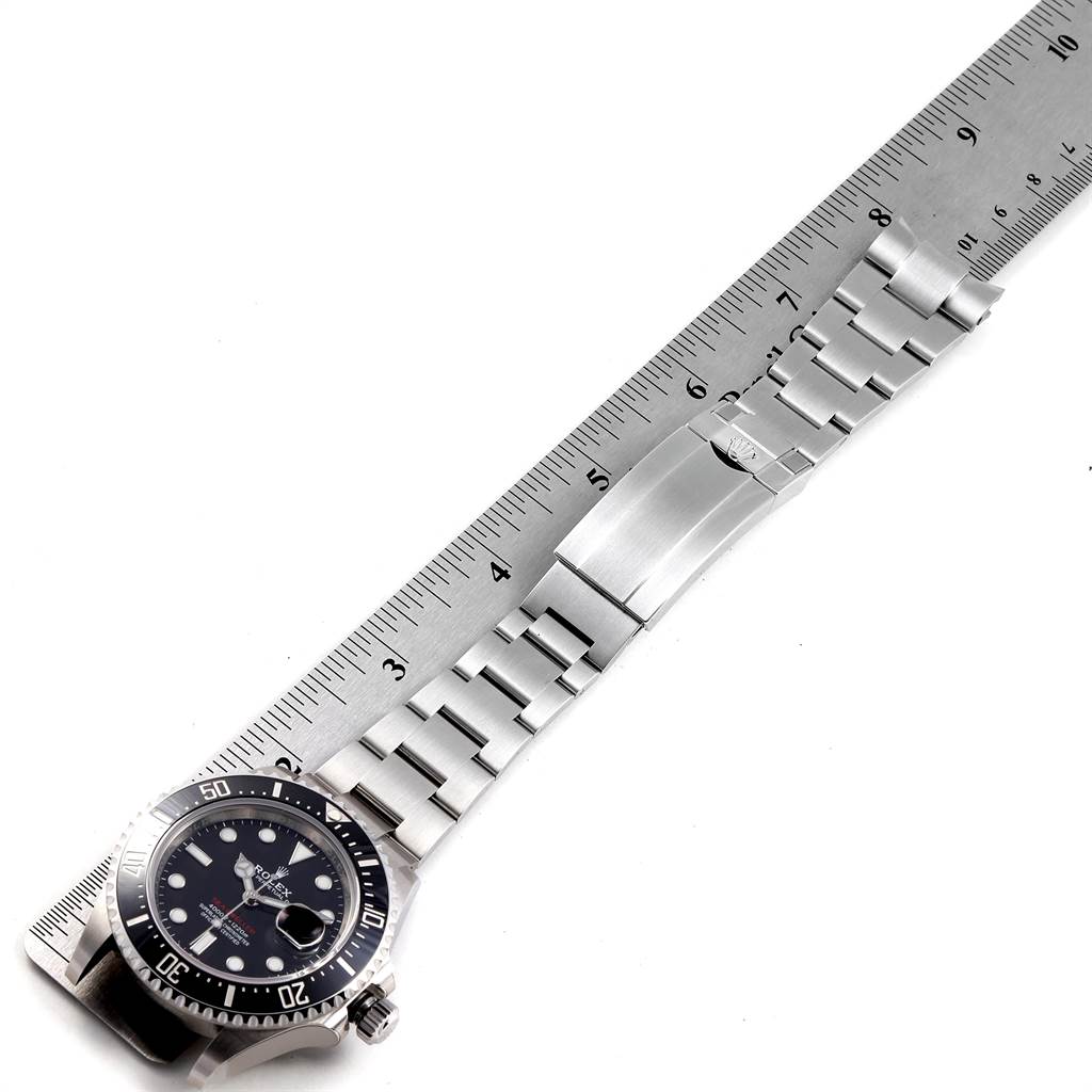 The image shows a Rolex Sea-Dweller 126600 Men
s Stainless Steel Black Dial 126600 Men
s Stainless Steel Black Dial watch laid flat with its bracelet and clasp alongside a ruler for measurement.