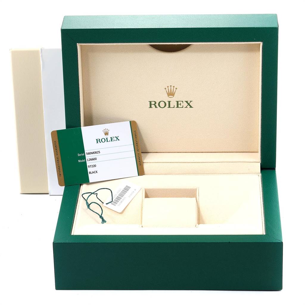 The image shows an open green and beige Rolex box for a Sea-Dweller model, along with a warranty card and a tag.