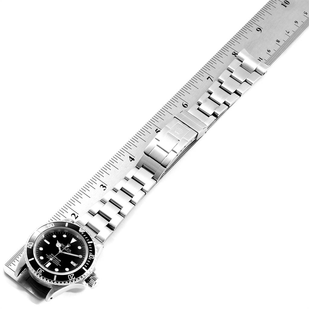 The image shows a top view of a Rolex Sea-Dweller 16600 Men
s Stainless Steel Black Dial 16600 Men
s Stainless Steel Black Dial watch placed alongside a ruler, displaying its bracelet and clasp.