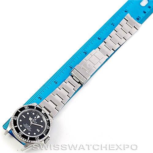 The image shows a top-down view of a Rolex Sea-Dweller 16600 Men's Stainless Steel Black Dial 16600 Men's Stainless Steel Black Dial watch with its metal bracelet and clasp, next to a blue ruler.
