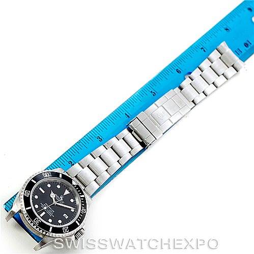 The image shows a top view of a Rolex Sea-Dweller 16600 Men
s Stainless Steel Black Dial 16600 Men
s Stainless Steel Black Dial watch with a stainless steel bracelet and clasp, placed alongside a blue ruler.