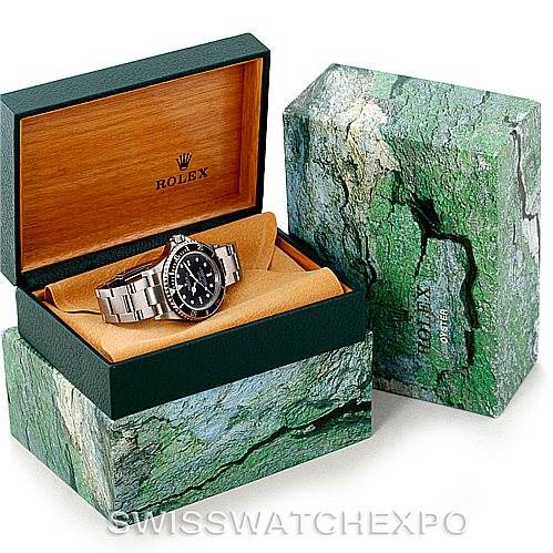 The image shows a Rolex Sea-Dweller 16600 Men
s Stainless Steel Black Dial 16600 Men
s Stainless Steel Black Dial watch in an open green and beige presentation box with the outer box also in the frame.